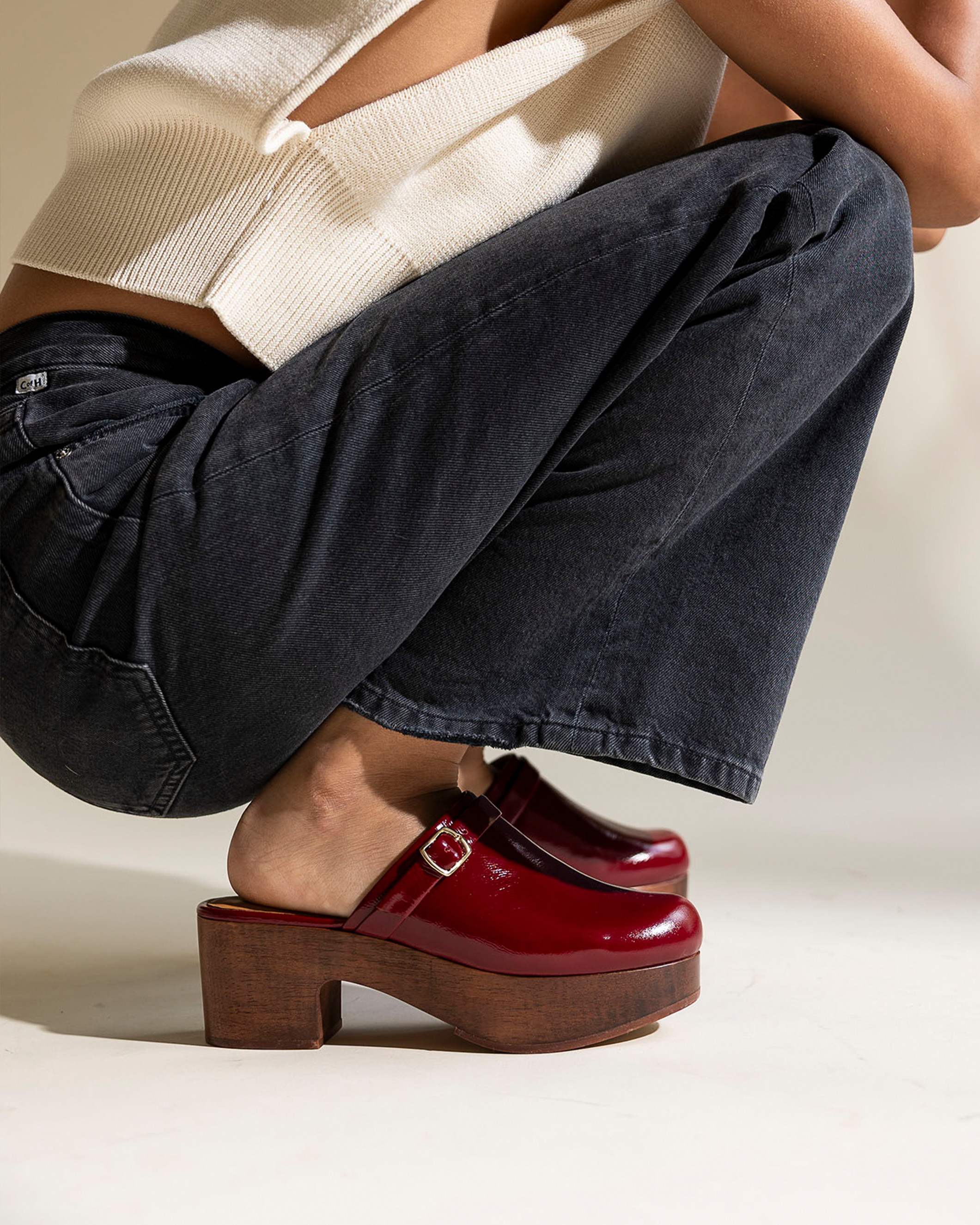 Person wearing red clogs with wooden soles on a neutral background