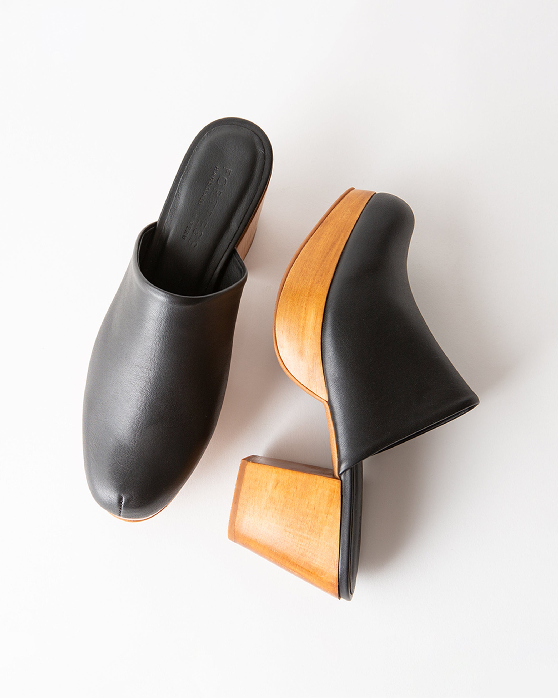 Pair of black and wooden clogs on a white background