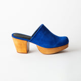 Blue suede clog shoe with wooden sole on a white background