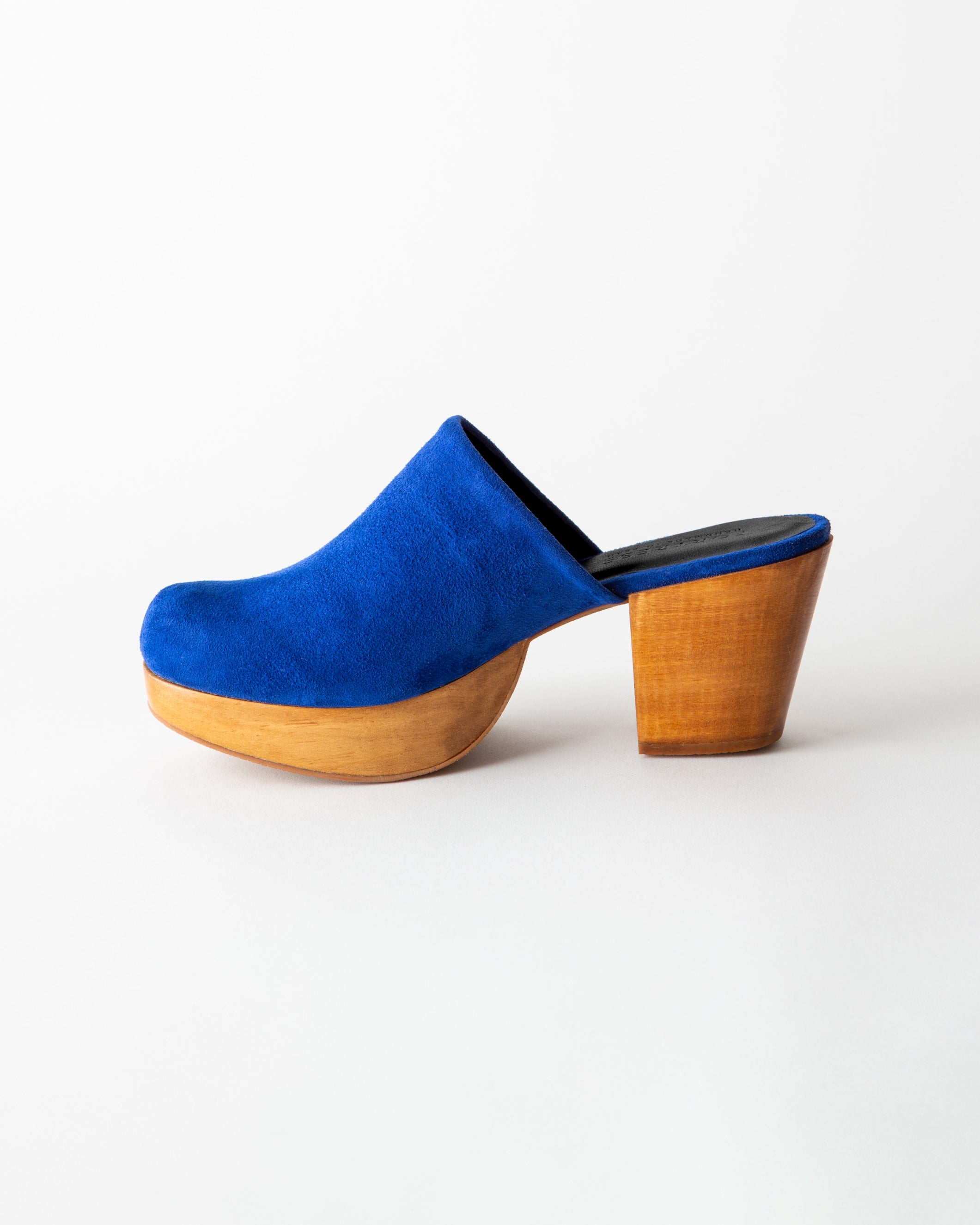 Blue suede clog shoe with wooden sole on a white background