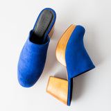 Blue suede mules with wooden soles on a white background