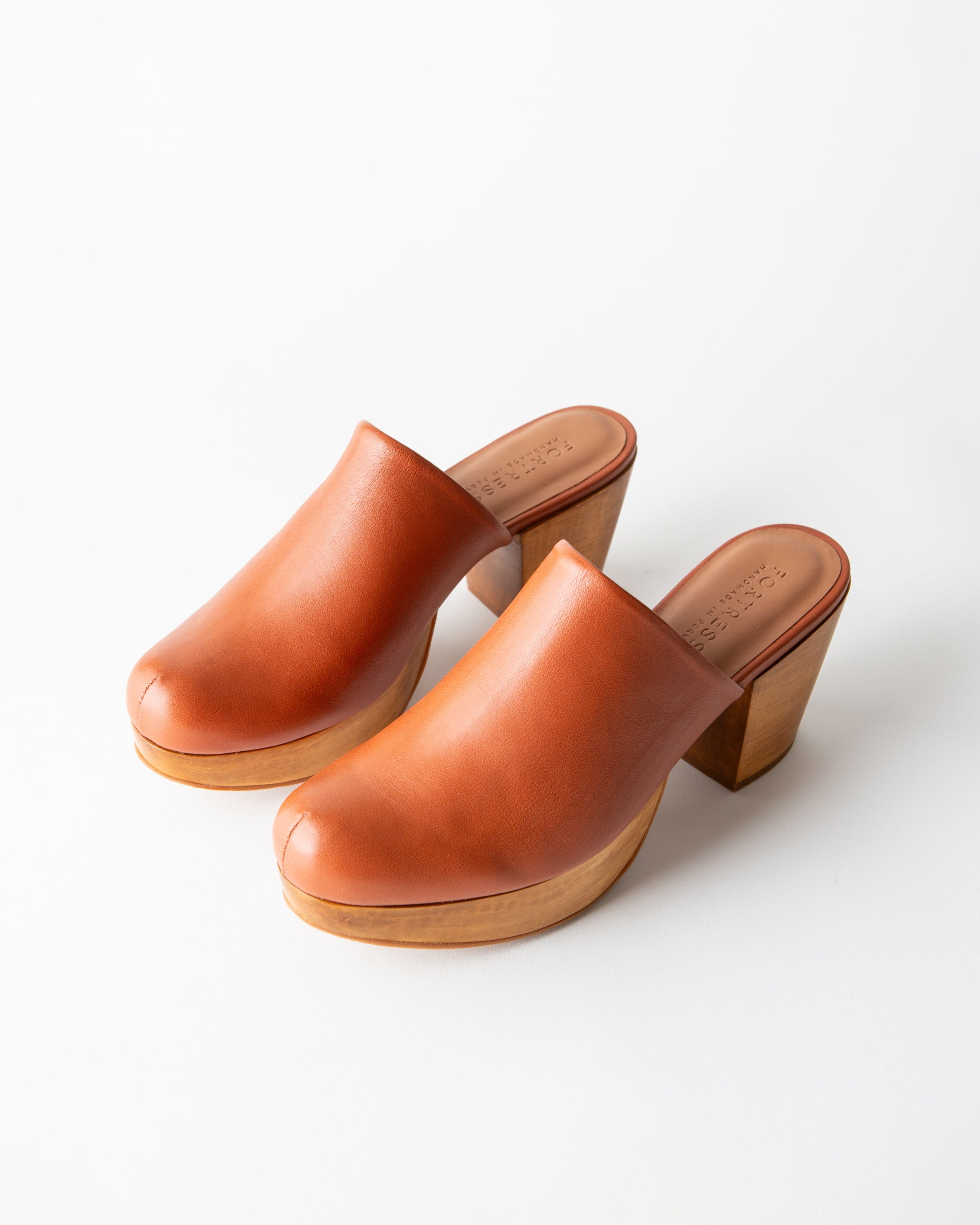 Pair of brown leather clogs on a white background