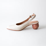 White shoe with wooden heel on a light gray background