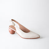 White shoe with wooden heel on a light gray background