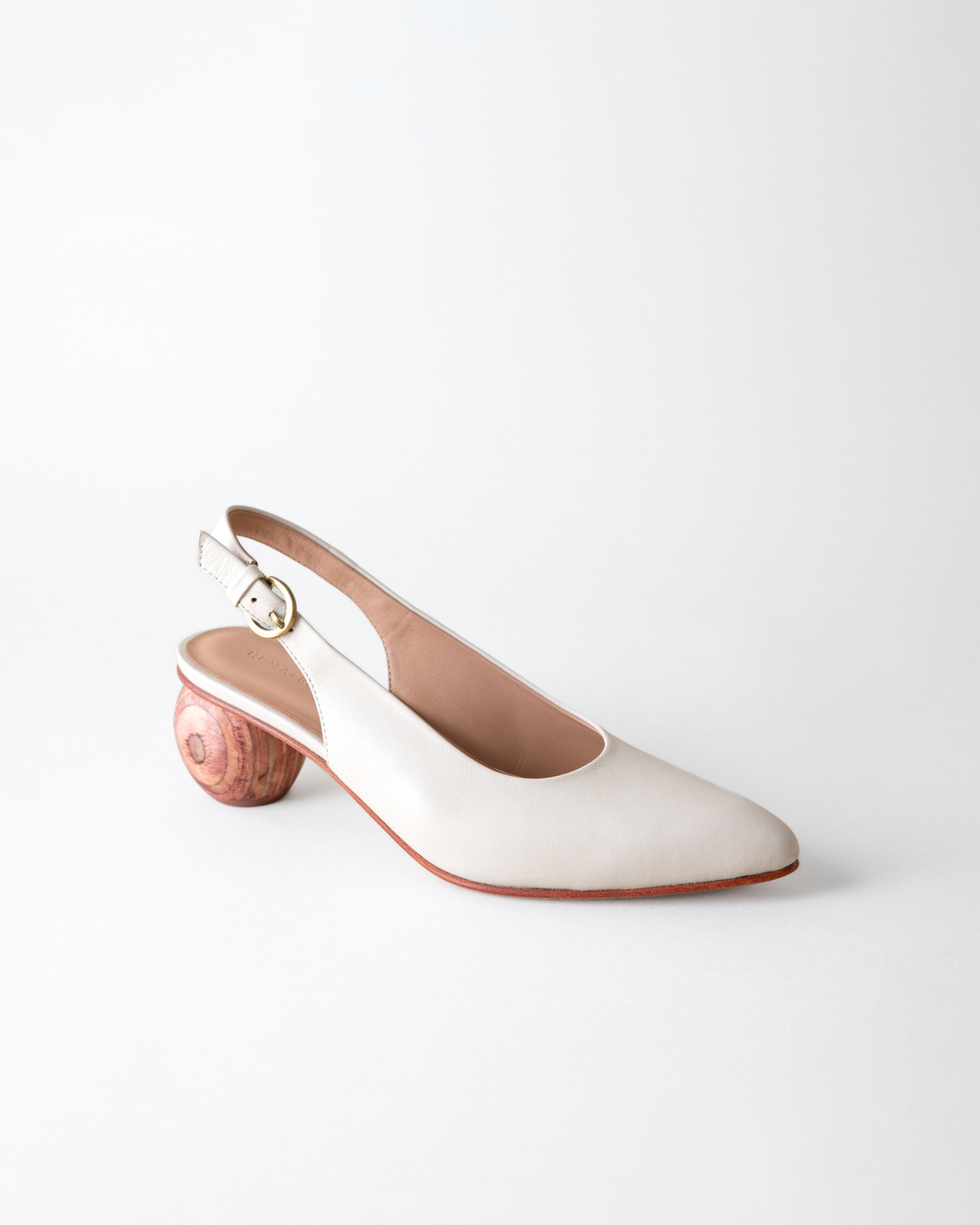 White shoe with wooden heel on a light gray background