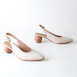 Pair of white slingback heels on a light gray background