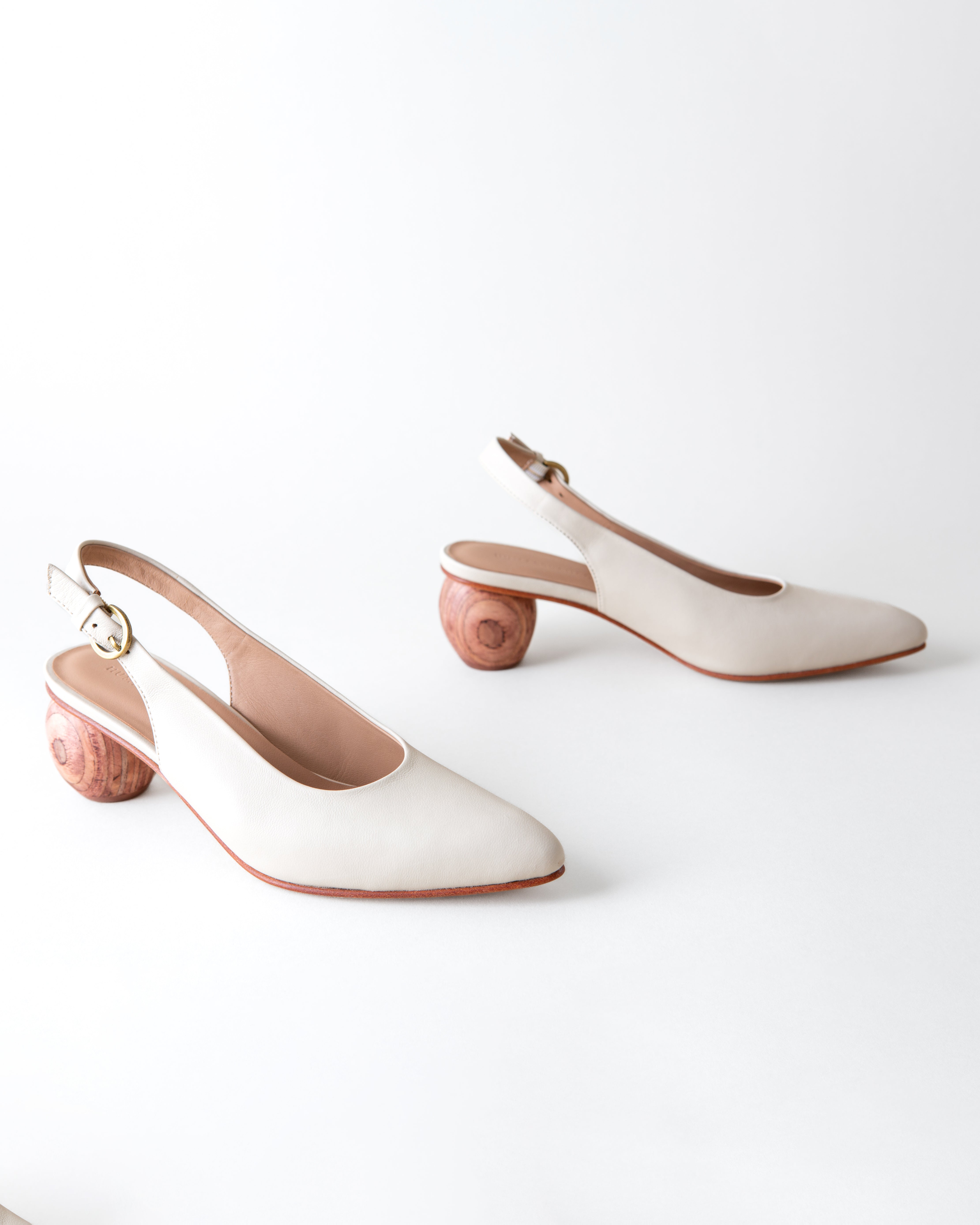 Pair of white slingback heels on a light gray background