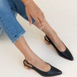 Black slingback shoes worn with blue jeans on a white background