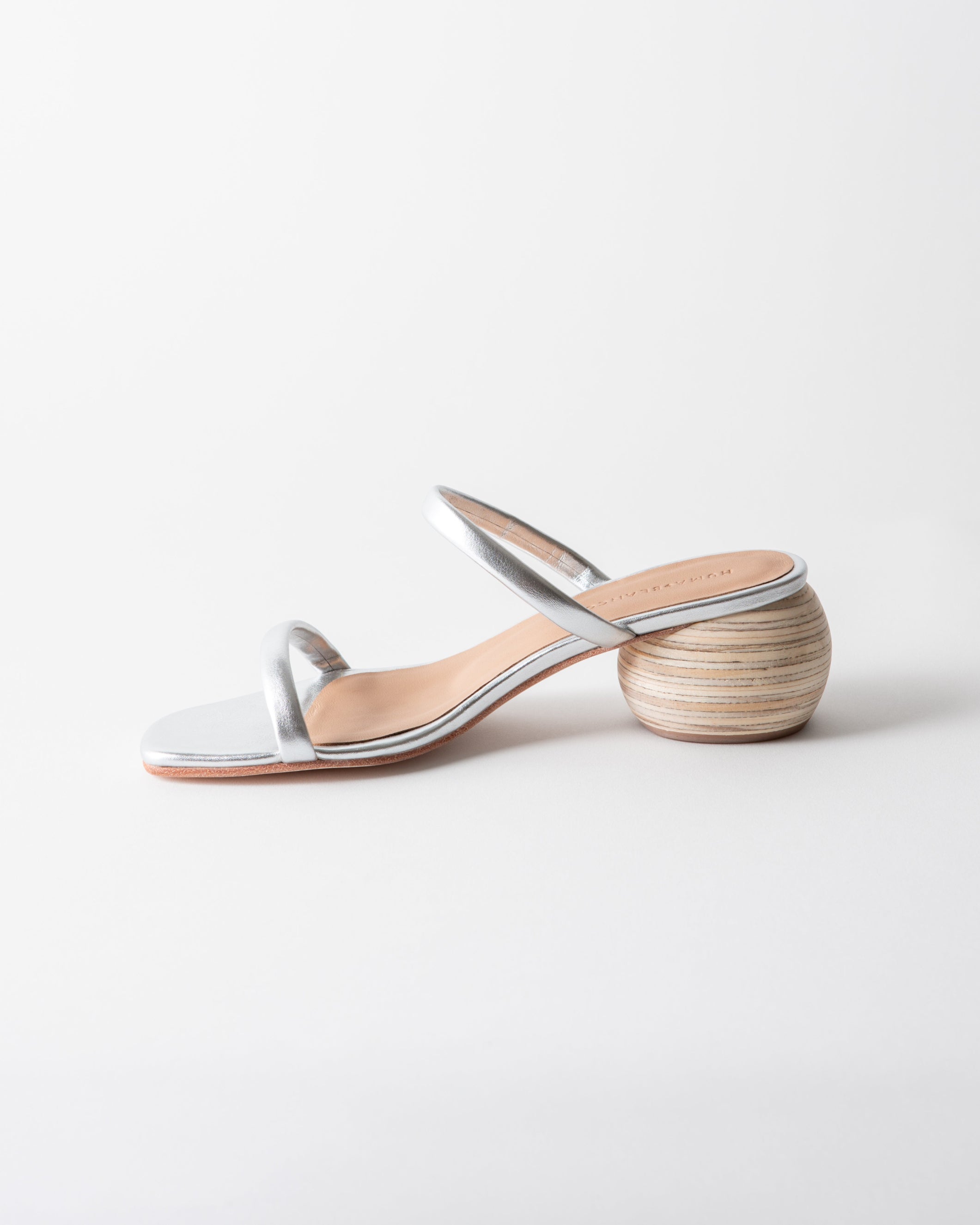 Silver sandal with wooden heel on a light gray background