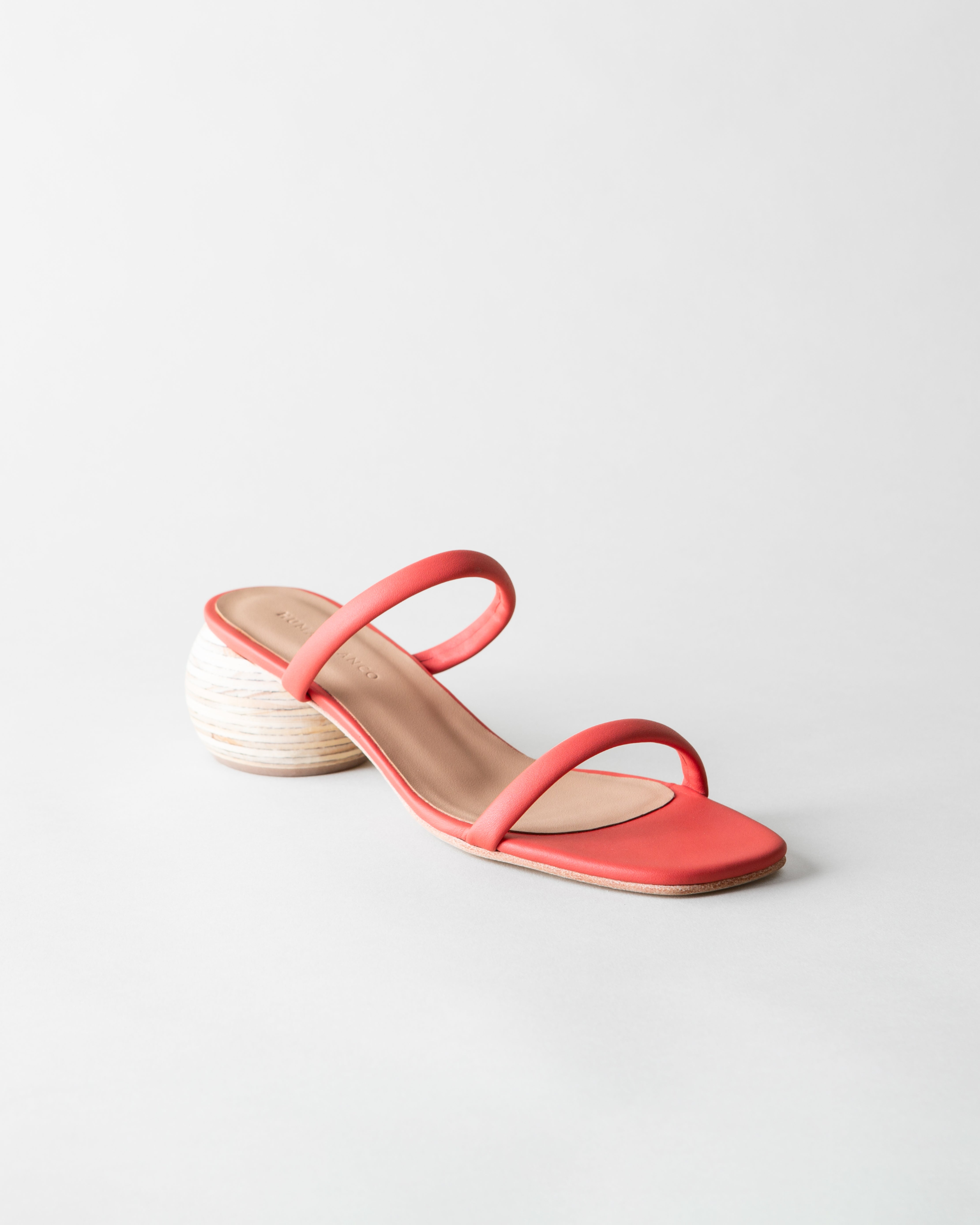 Coral sandal with a wood heel on a light gray background