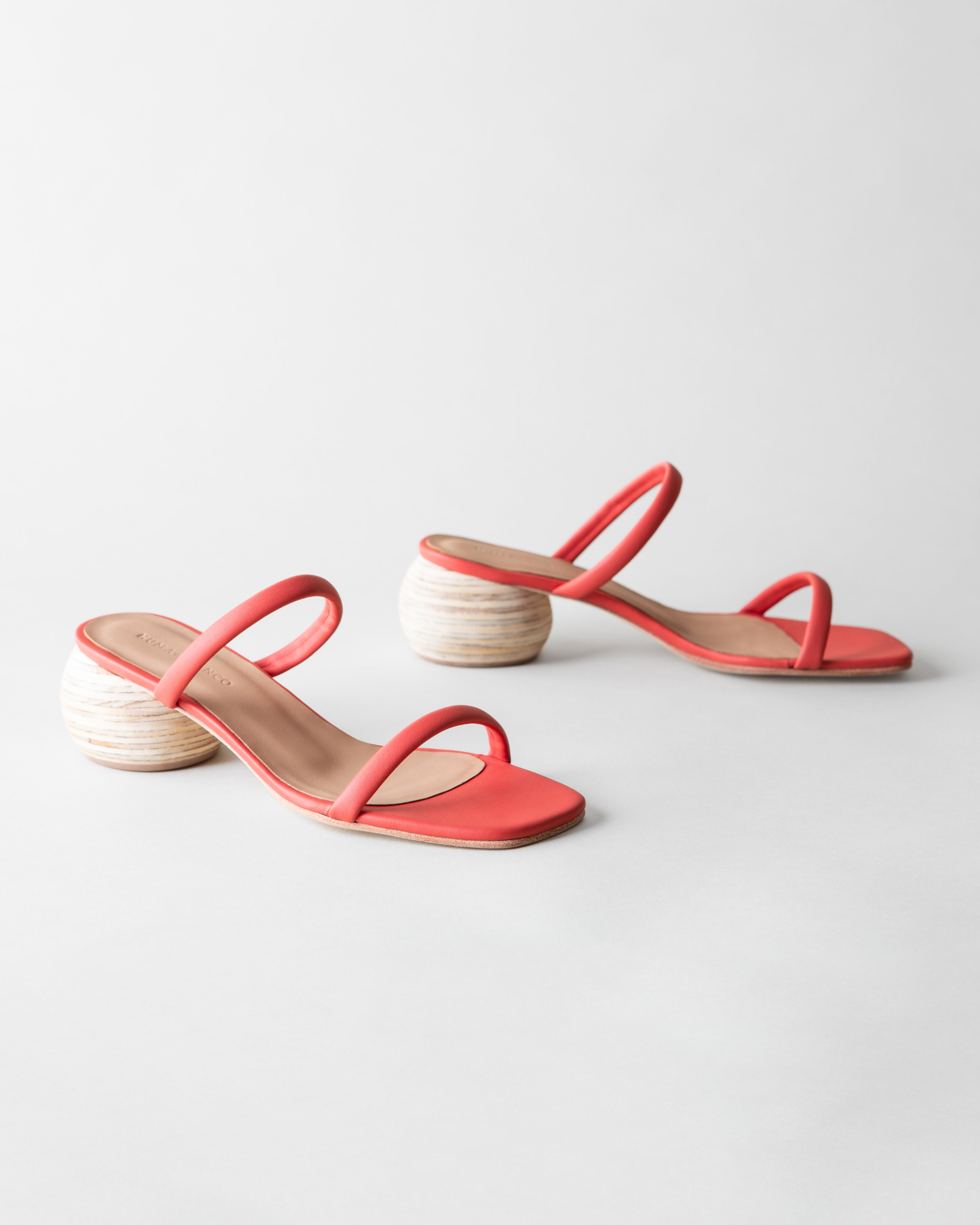 Coral sandals with wooden heels on a light gray background