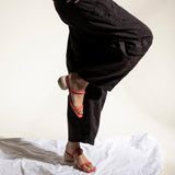 Person wearing black pants and red sandals on a white surface with a neutral background