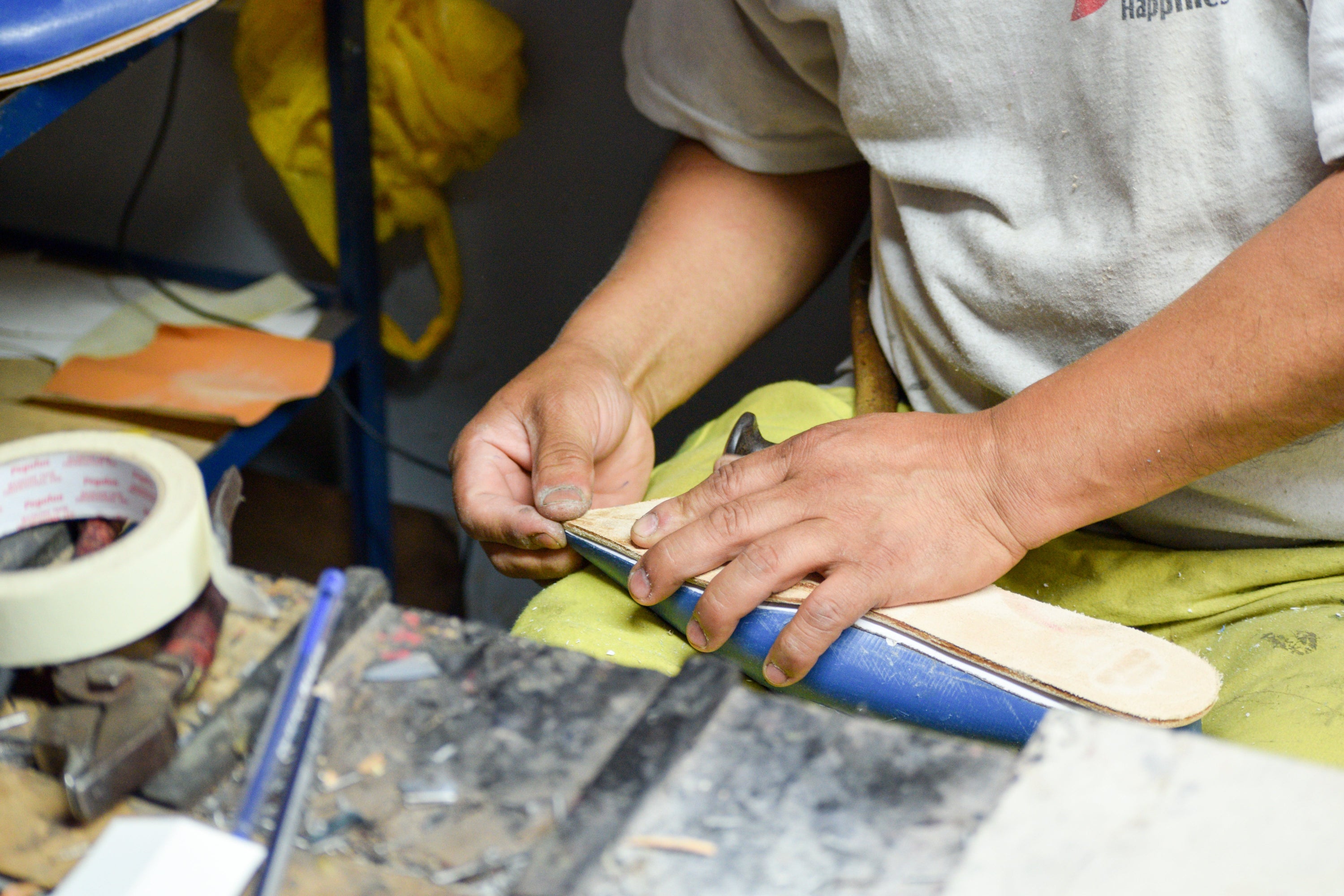 Person working on a shoe with tools and materials in a workshop setting