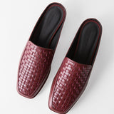 A pair of women's slip-on mule loafers with a woven leather upper and square toes, shown from a top-down angle on a light gray background. The shoes are a deep burgundy/wine color with a black insole.