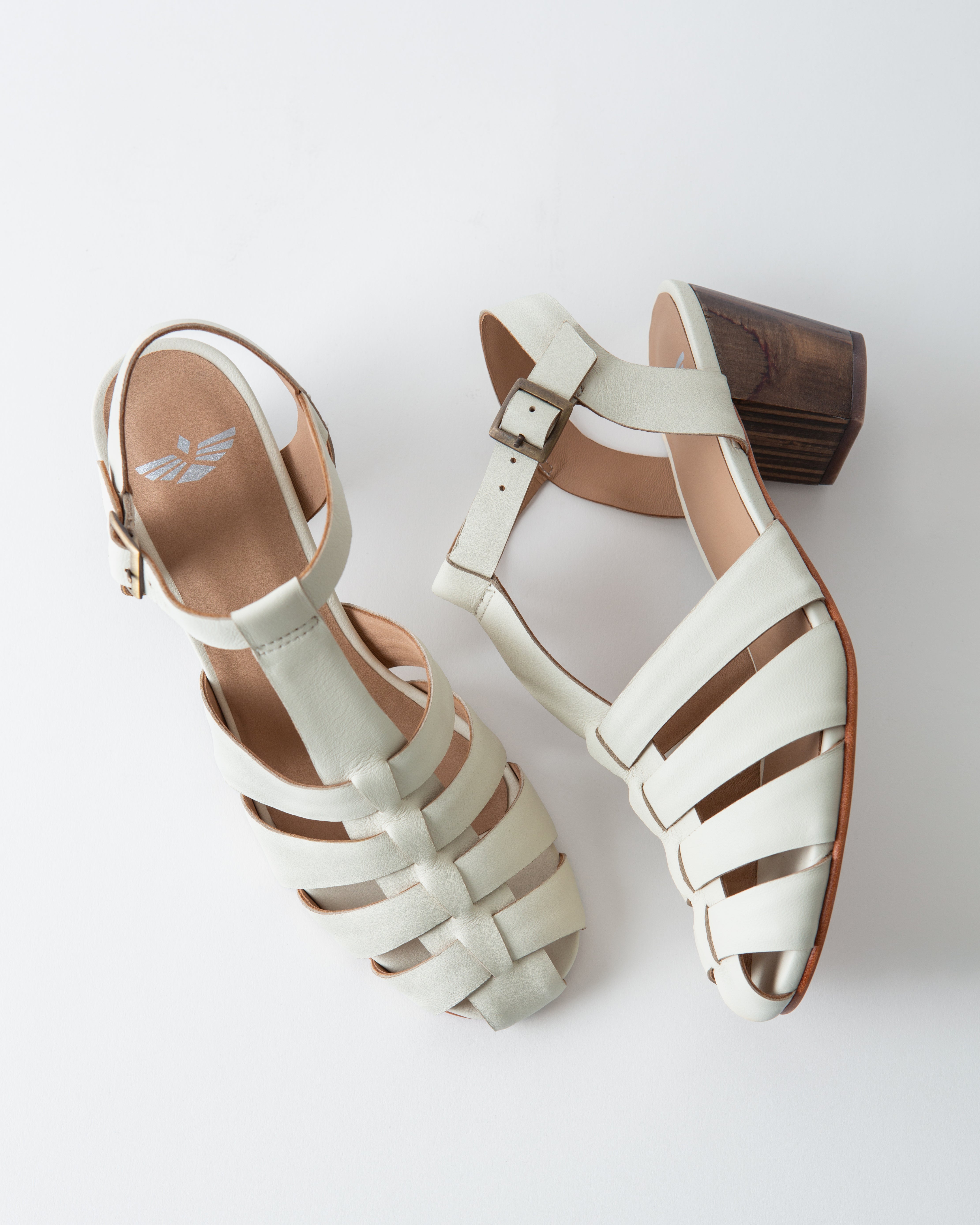 Pair of white sandals with brown soles on a light gray background