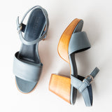 Pair of light blue sandals with a wooden heel on a white background