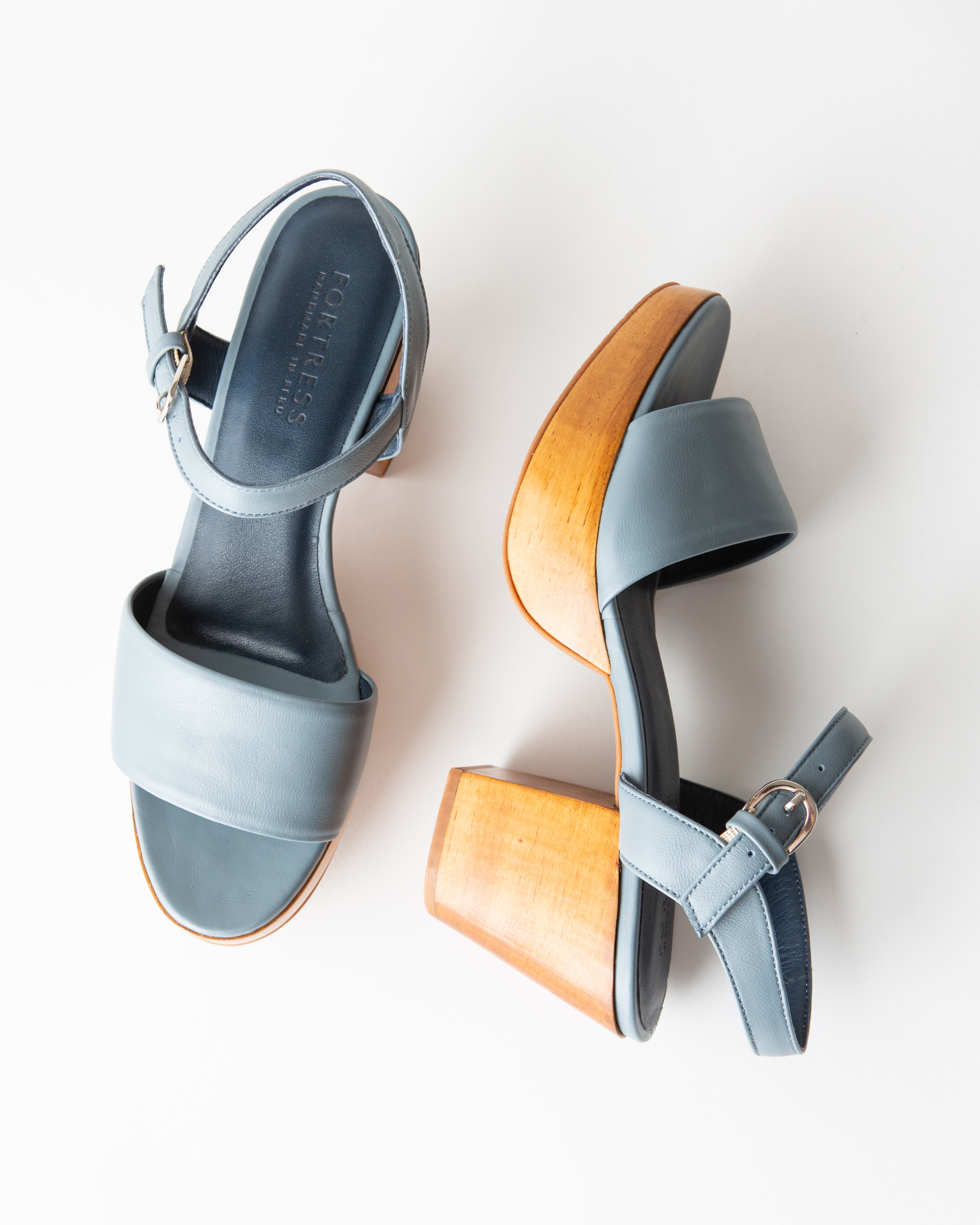 Pair of light blue sandals with a wooden heel on a white background