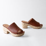 Pair of brown leather clogs with wooden soles on a white background