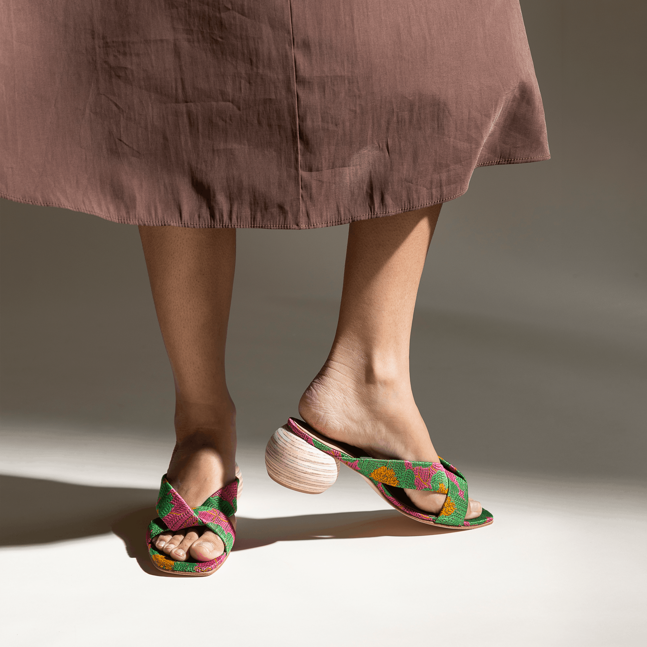 Person wearing pink and green floral sandals with a neutral background