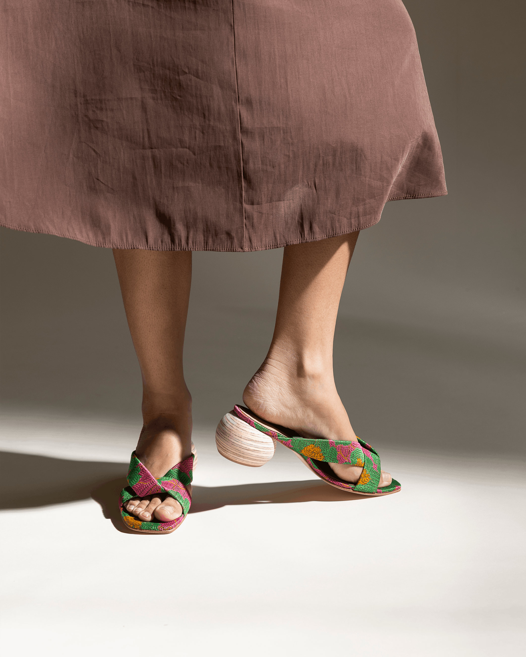 Person wearing pink and green floral sandals with a neutral background