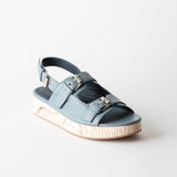 Blue sandal with metallic accents on a light gray background