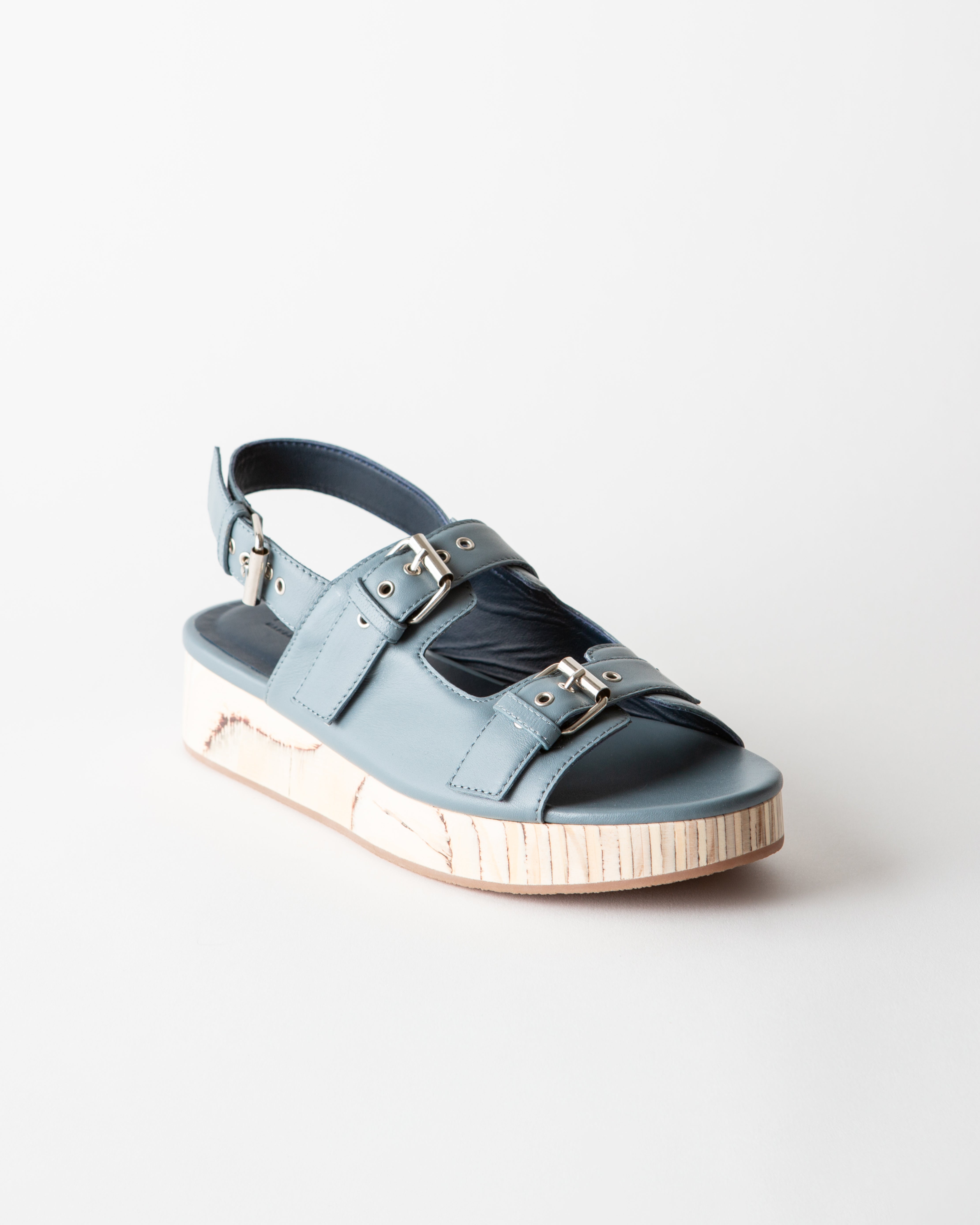 Blue sandal with metallic accents on a light gray background