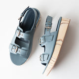 Pair of light blue sandals with wooden soles on a white background
