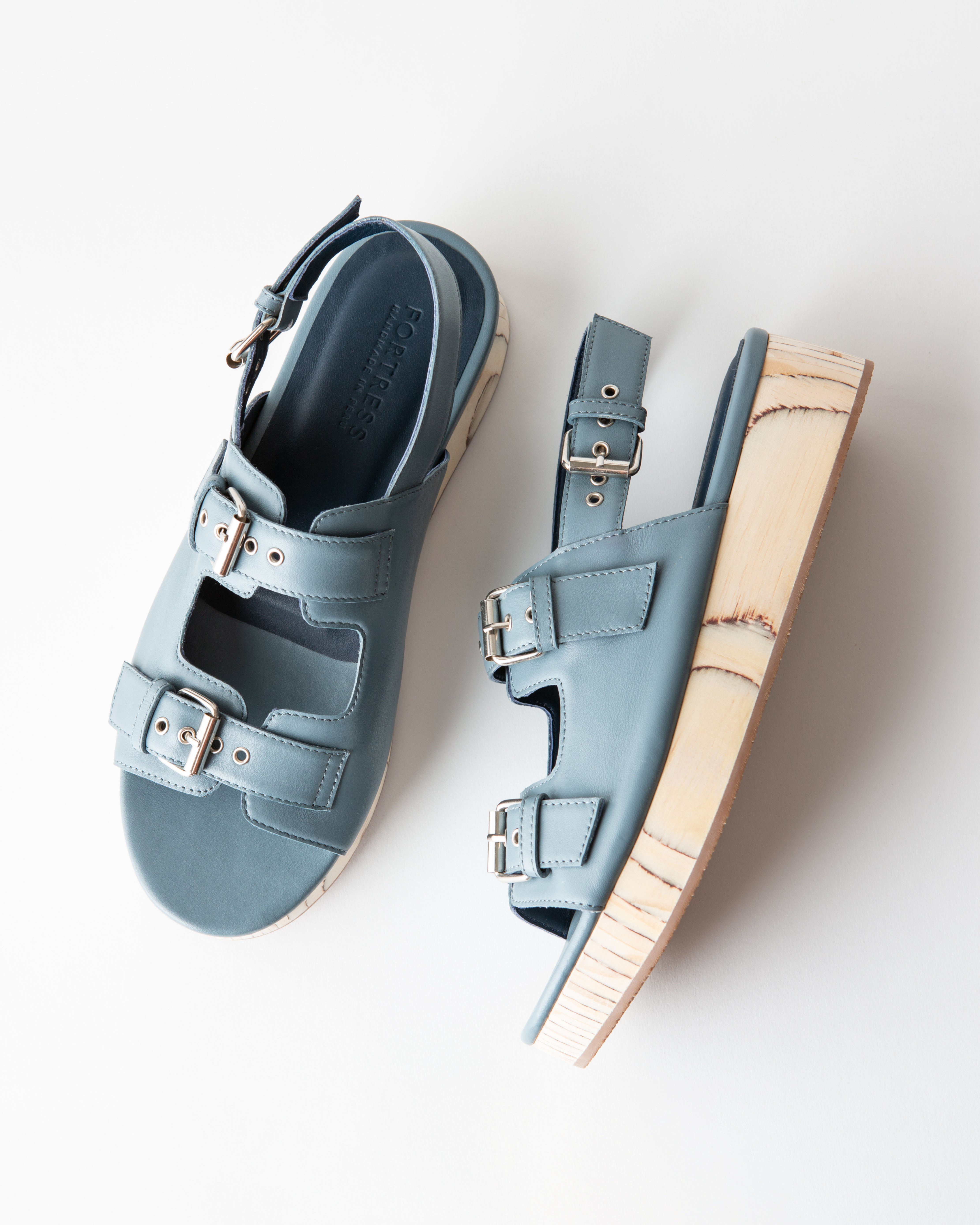 Pair of light blue sandals with wooden soles on a white background