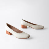 Pair of white shoes with wooden soles on a light gray background