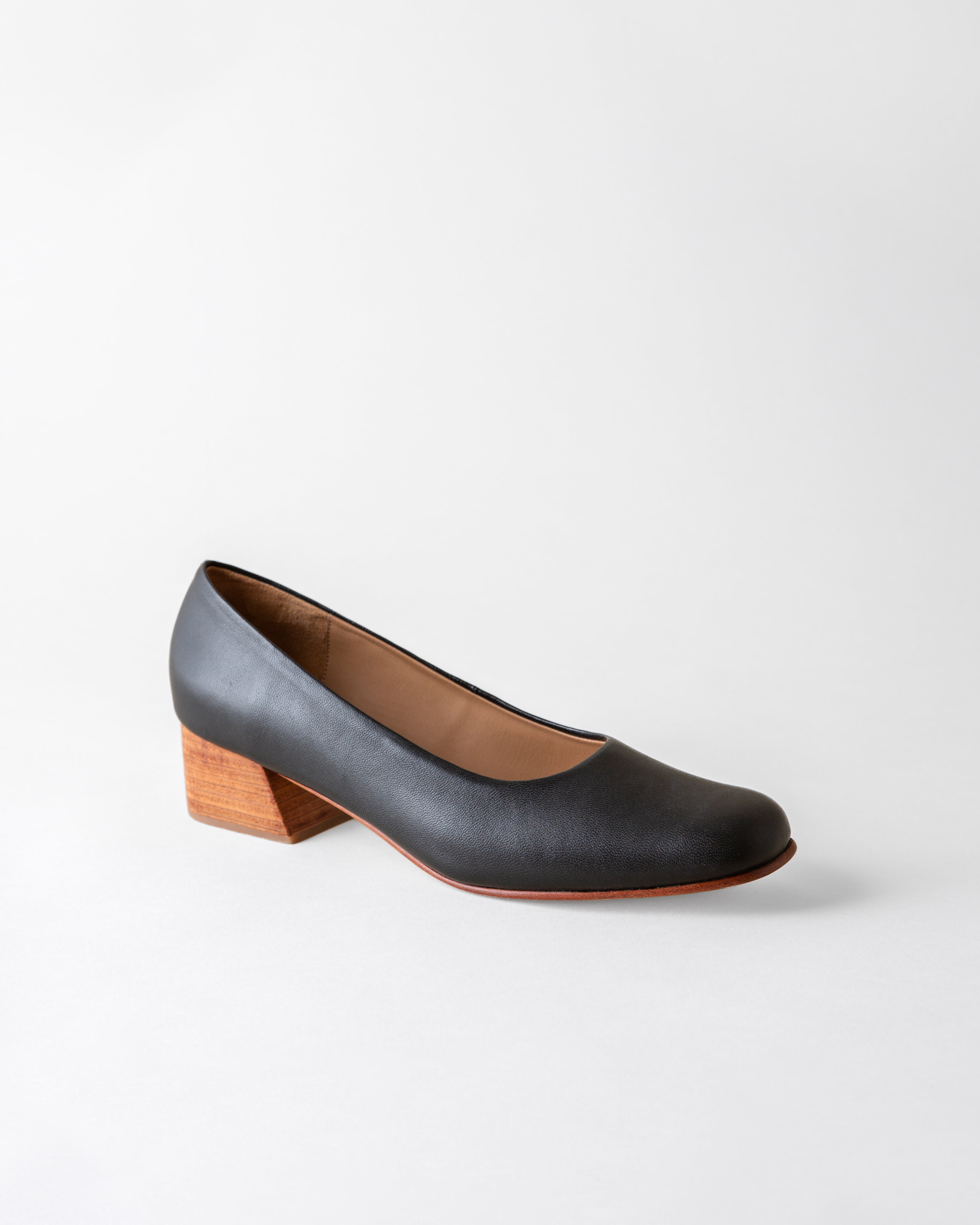 Black shoe with a wooden heel on a light gray background
