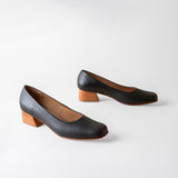 Pair of black leather shoes with wooden soles on a white background