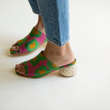 Colorful open-toe shoes worn with blue jeans on a white background