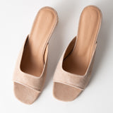 Pair of beige open-toe mules on a white background