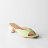 Green sandal with a wooden heel on a light gray background