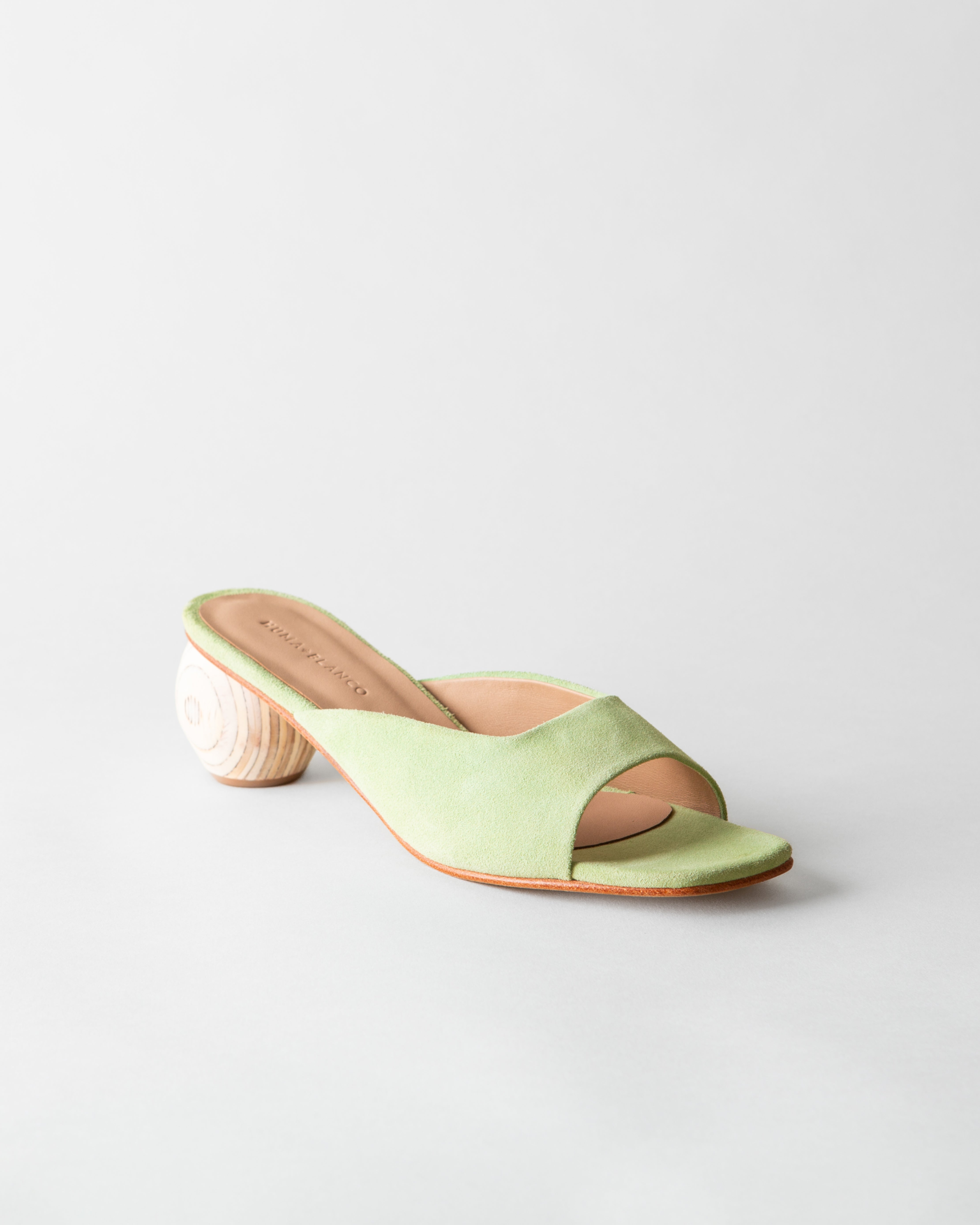 Green sandal with a wooden heel on a light gray background