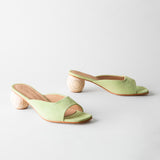 Pair of light green sandals with wooden block heels on a white background