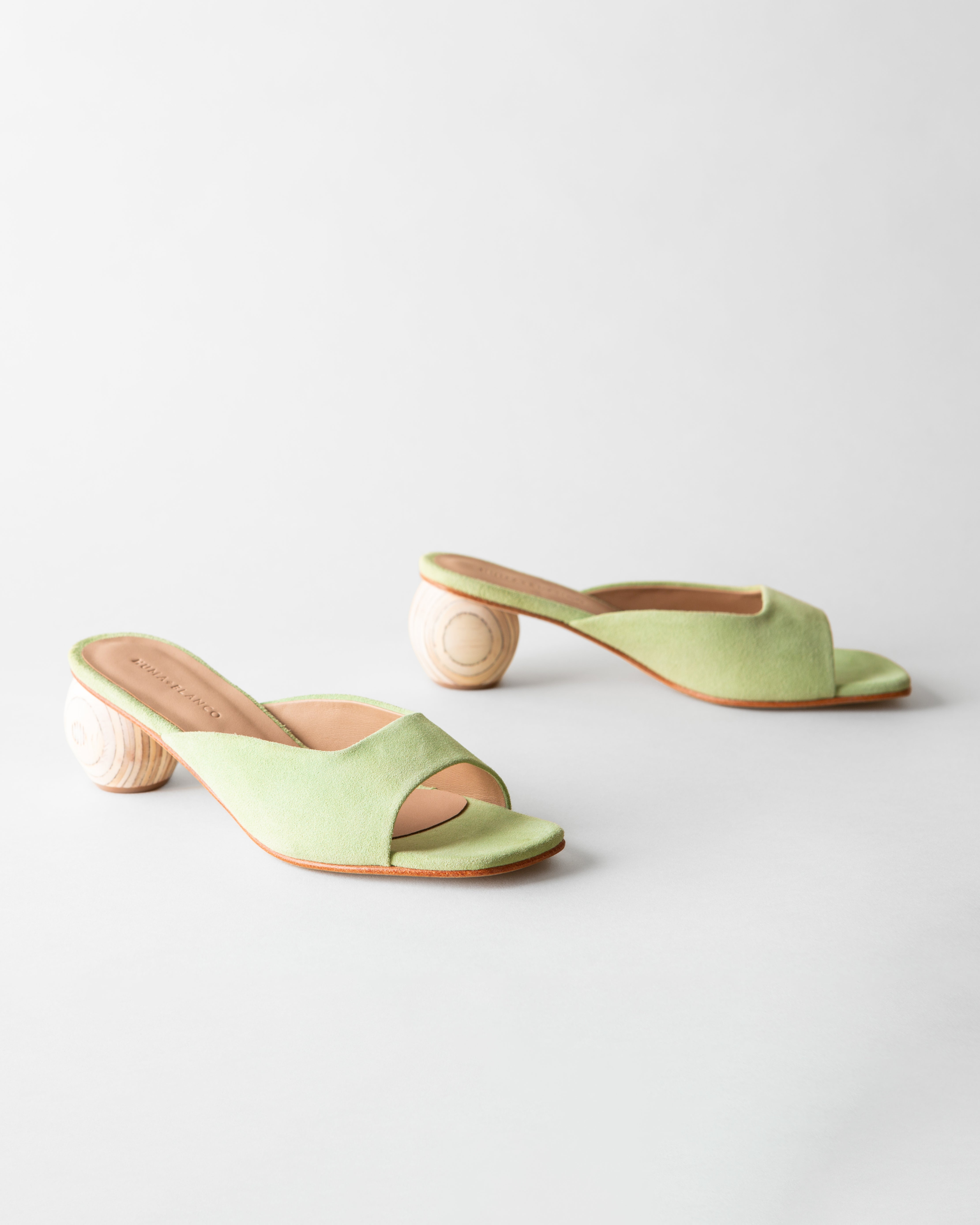Pair of light green sandals with wooden block heels on a white background