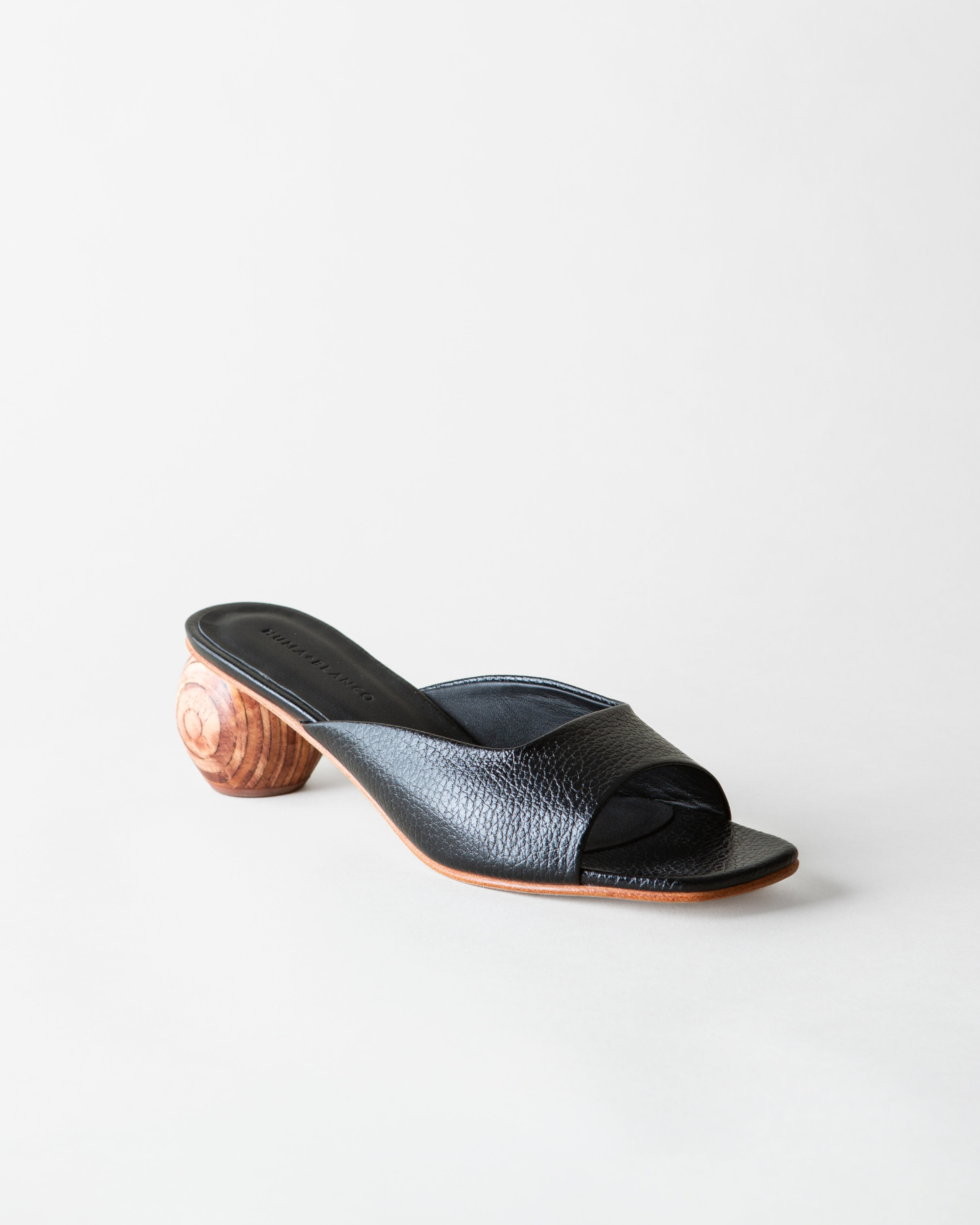 Black open-toe sandal with wooden heel on a white background