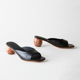 Pair of black open-toe shoes with wooden heels on a white background