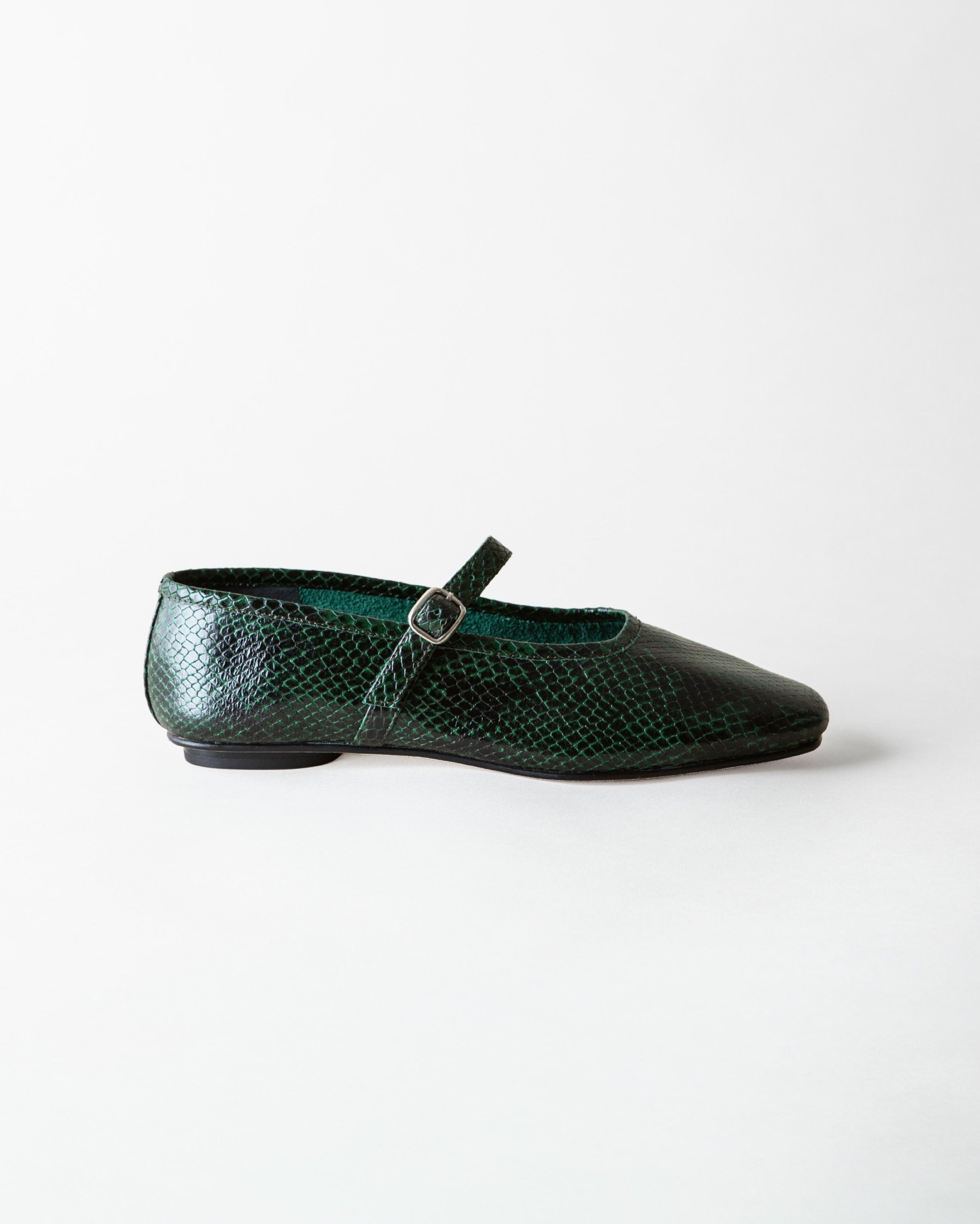 A single dark green snakeskin Mary Jane flat shoe with a pointed toe and a small silver buckle, shown in profile against a light gray background.