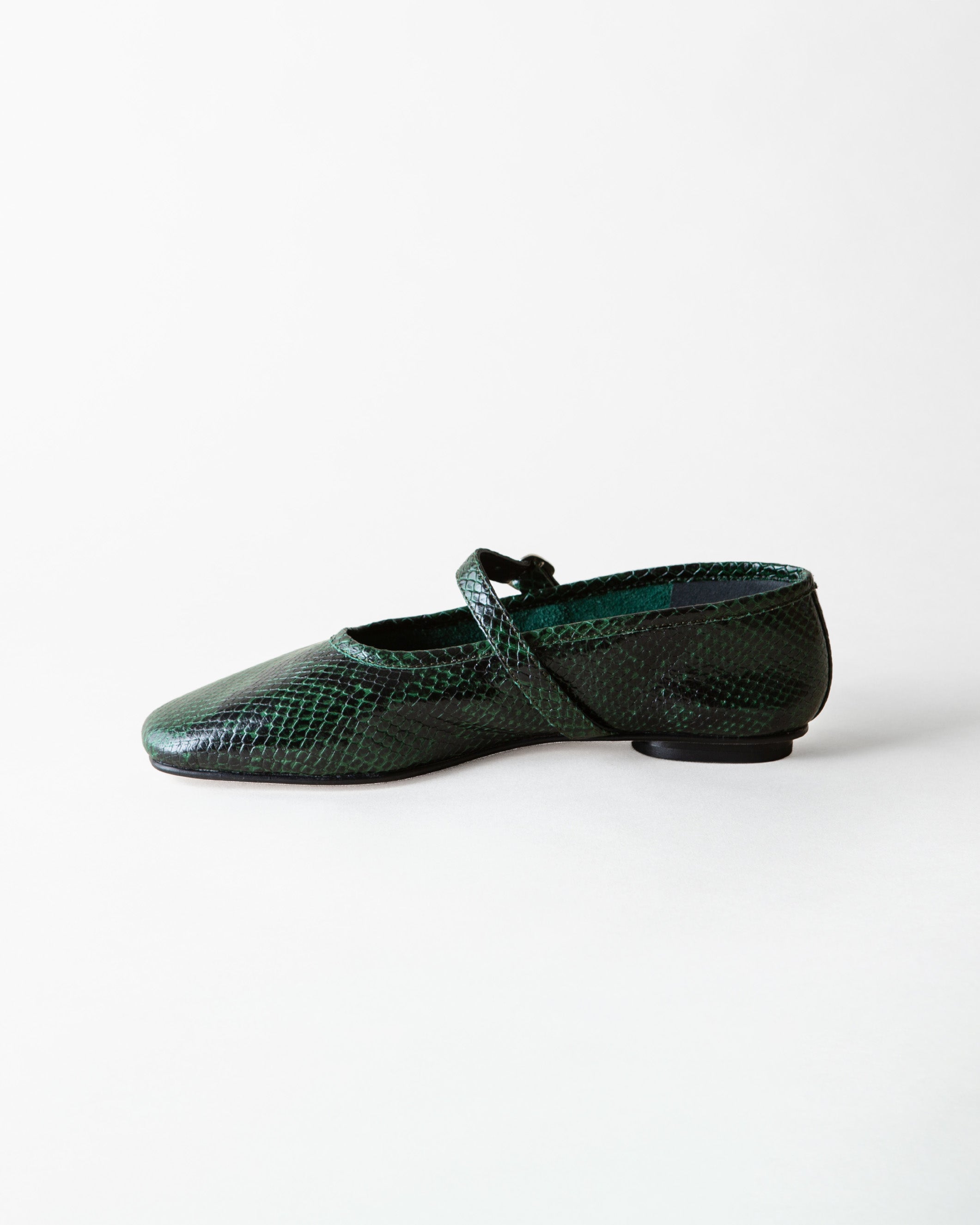 A single dark green snakeskin-patterned flat shoe with a Mary Jane strap, shown in profile against a plain white background.