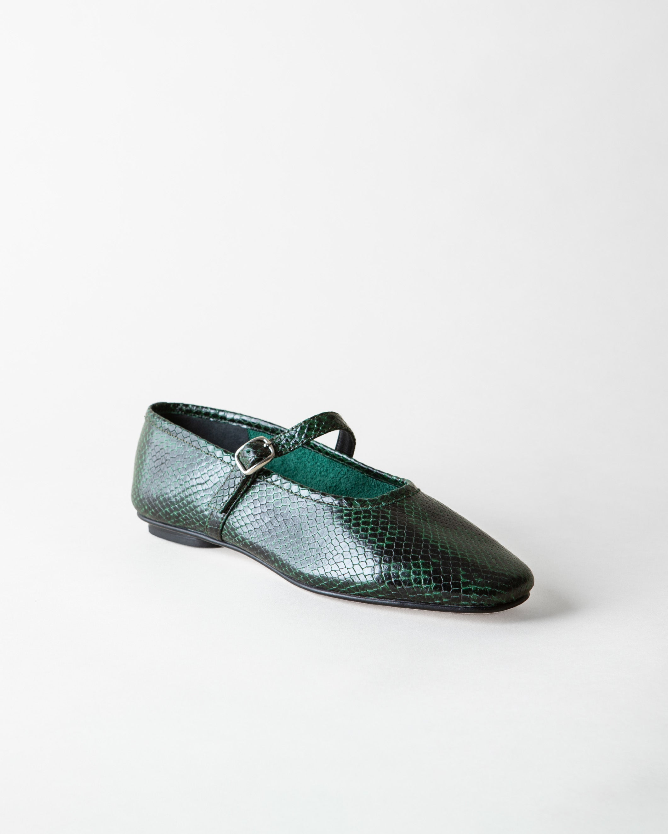 A single dark green snakeskin-textured Mary Jane flat shoe with a small silver buckle, shown on a light gray background.