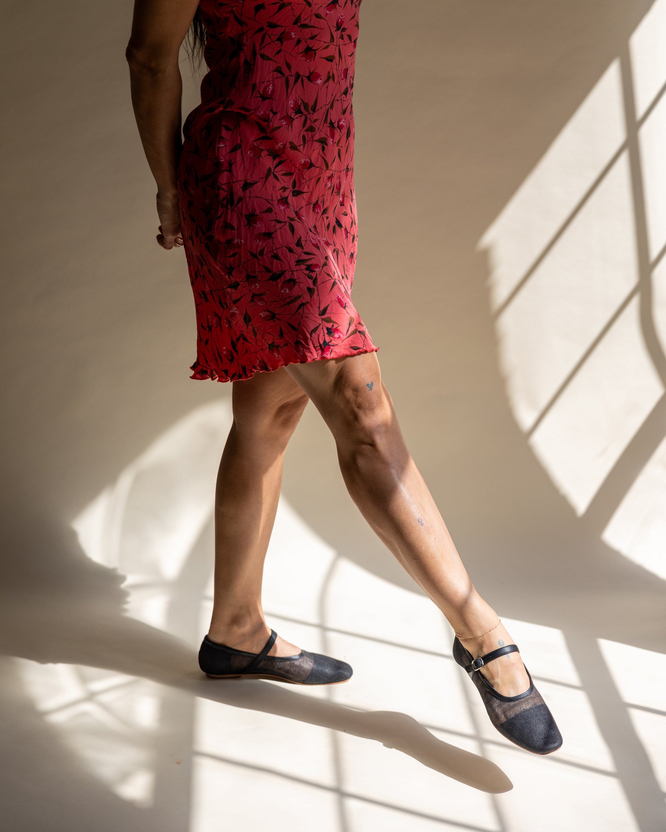 Model wearing a red floral dress and black jute ballet flats