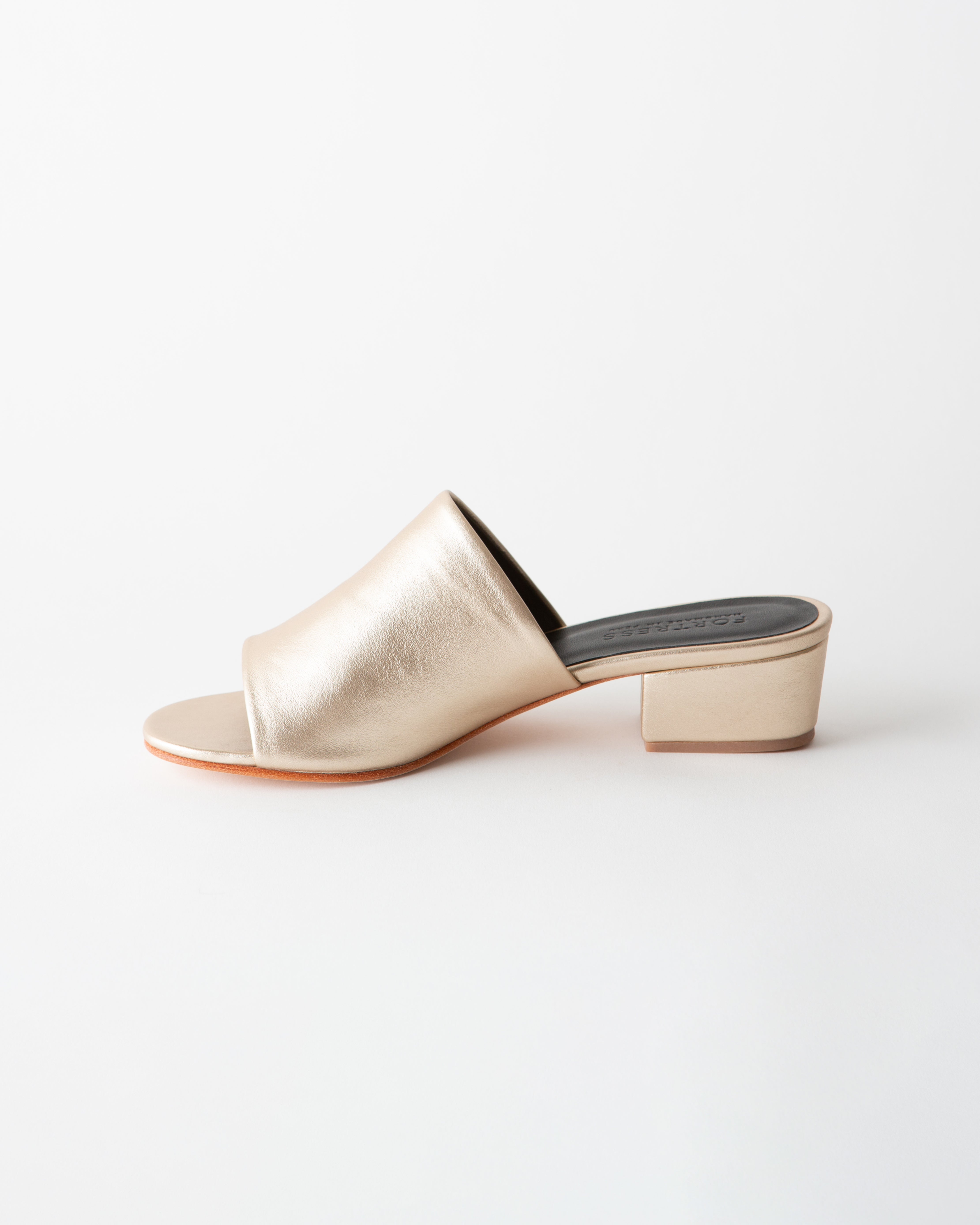Gold metallic sandal with a block heel on a white background