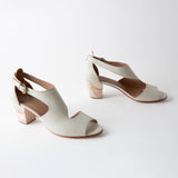 Pair of white sandals with wooden block heels on a white background
