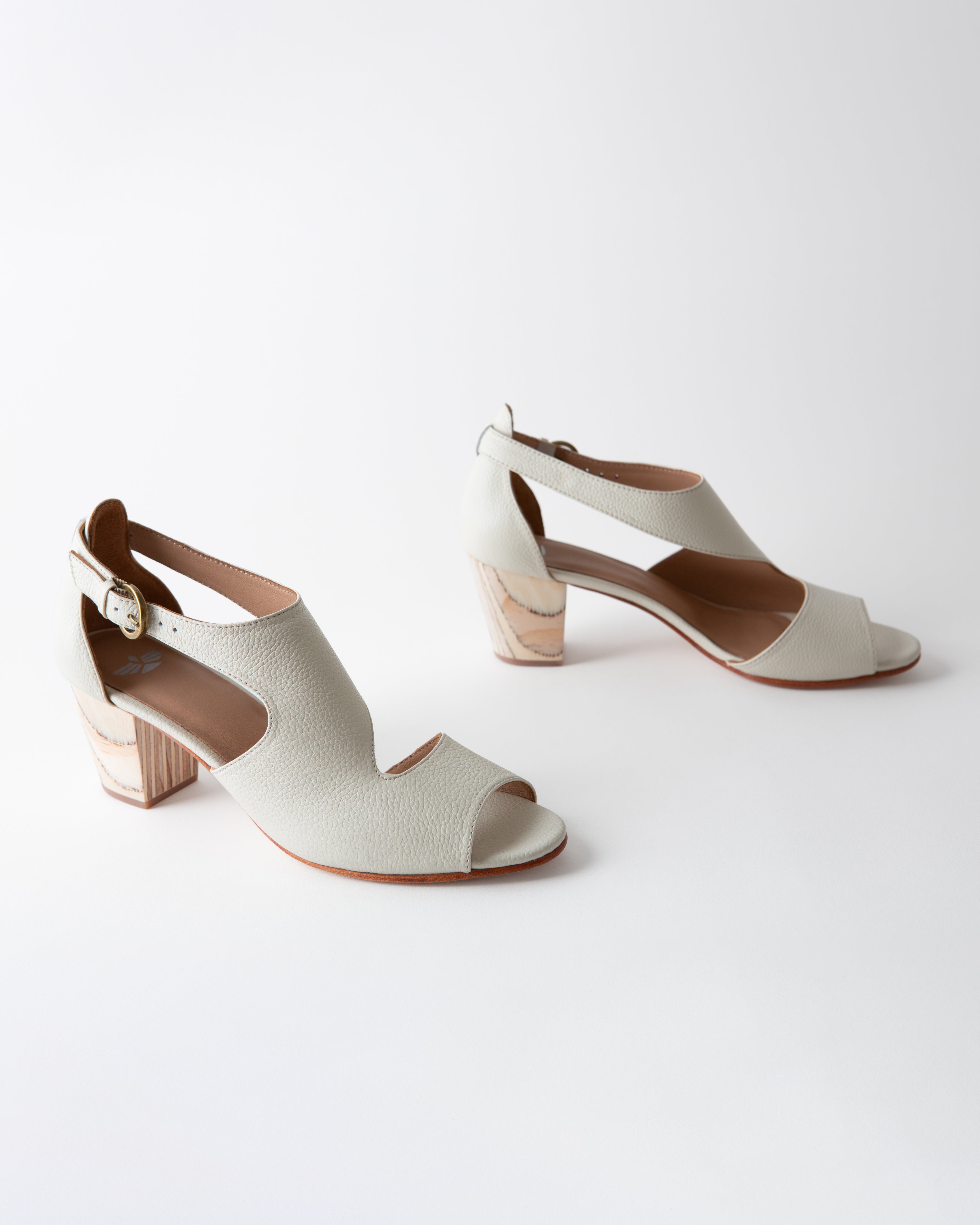 Pair of white sandals with wooden block heels on a white background