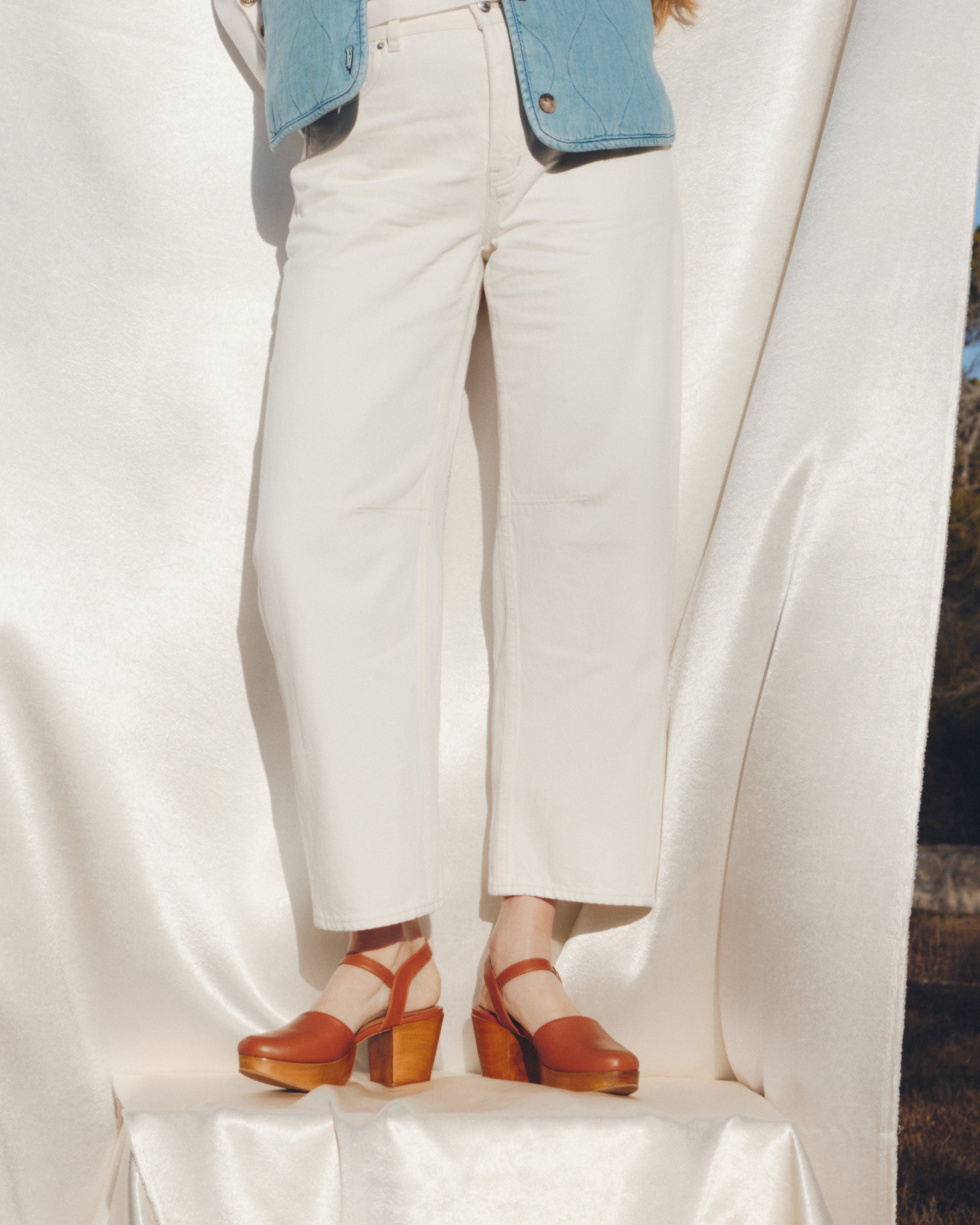 Person wearing white pants and brown sandals on a white background