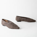 A pair of pointed-toe flat shoes with a woven basket-like texture in a dark taupe-brown color, displayed on a clean white background.