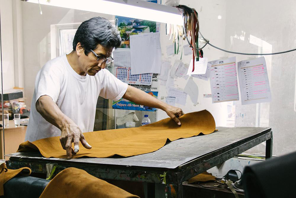 Image from Pedro + Marta's workshop of a shoemaker laying out leather and cutting shoe patterns